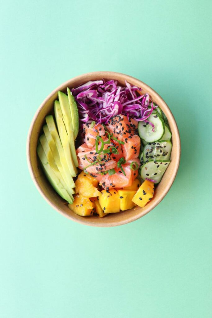 eine leckere Bowl mit Avocado, Lachs, Kürbis, Rotkohl, Gurken und noch viel mehr