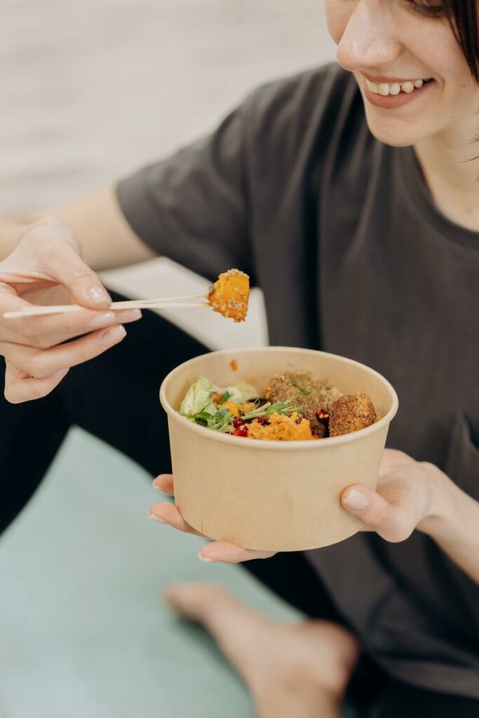 eine Frau isst eine Bowl mit Kürbis und Falaffel, Salat und Gemüse