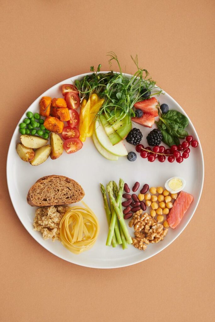 Teller mit gesundem Essen, Gemüse, Obst, Vollkornbrot, Hülsenfrüchten, Fisch